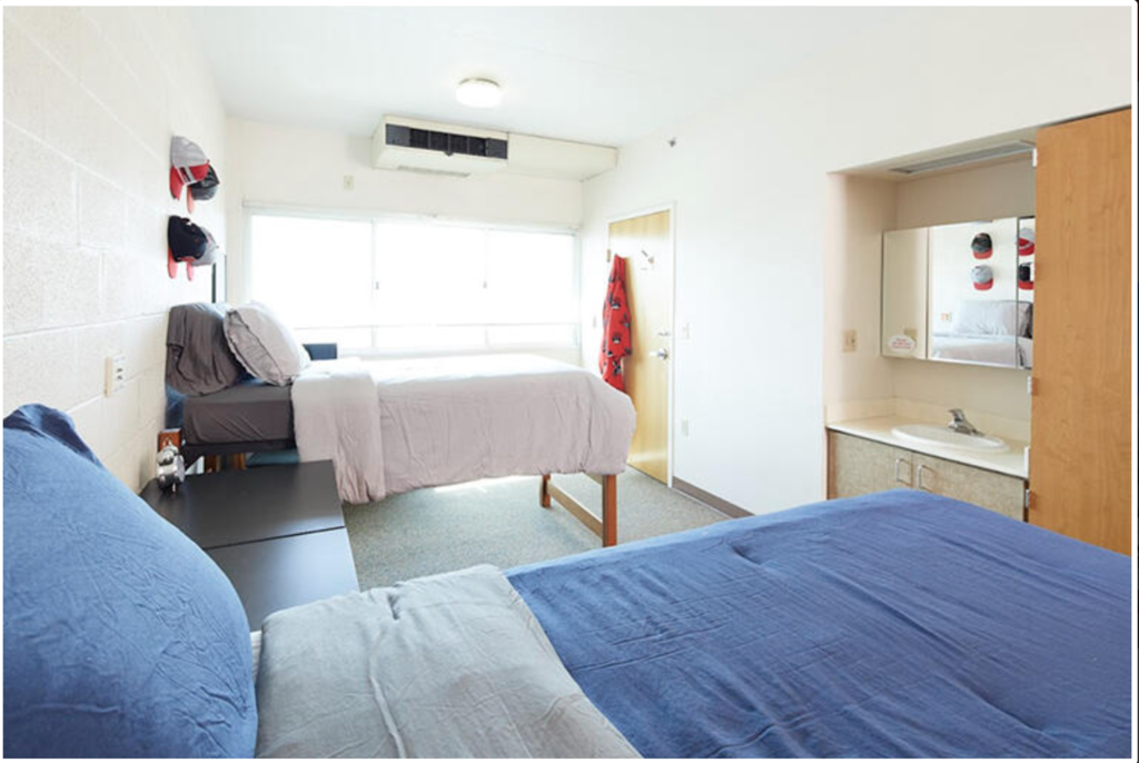 Dorm room in Tonopah Complex at UNLV. Room has two beds, a sink, and cabinets.